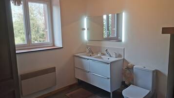 Een moderne badkamer met een wit wastafelmeubel, spiegel en toilet.