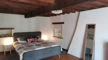 Une chambre à coucher avec un lit, des tables de chevet, un miroir et un plafond en bois.