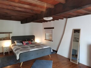 A bedroom with a bed, bedside tables, a mirror, and a wooden ceiling.