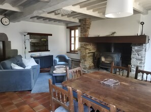A cozy living room with a stone fireplace, a dining table, and a blue sofa.