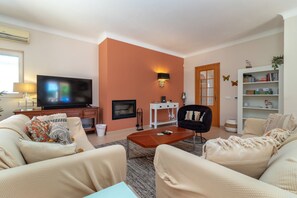 A living room with a television, sofa, coffee table, and a bookshelf. - Casa Oásis - 3 Bedroom Villa With Heatead Pool In Carvoeiro (Carvoeiro)