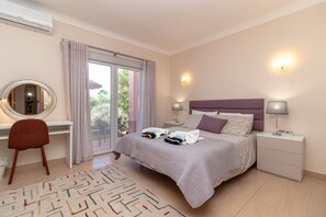 A hotel room with a bed, a desk, a chair, a mirror, a nightstand, and a lamp. - Casa Oásis - 3 Bedroom Villa With Heatead Pool In Carvoeiro (Carvoeiro)