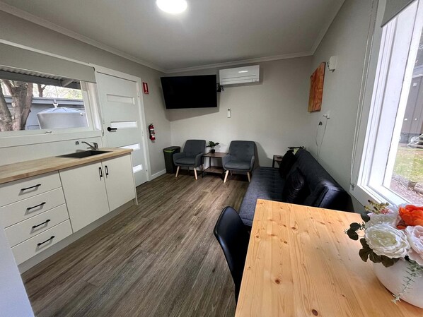 A compact living space with a kitchenette, a dining area, and a seating area with a sofa and chairs.