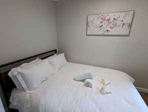 A neatly made bed with white linens, a rolled towel, and a small tray with a fork and spoon. - Glamping Cabin in Dadswells Bridge, Ideal for an Outdoor Adventure in the Grampians (Dadswells Bridge)