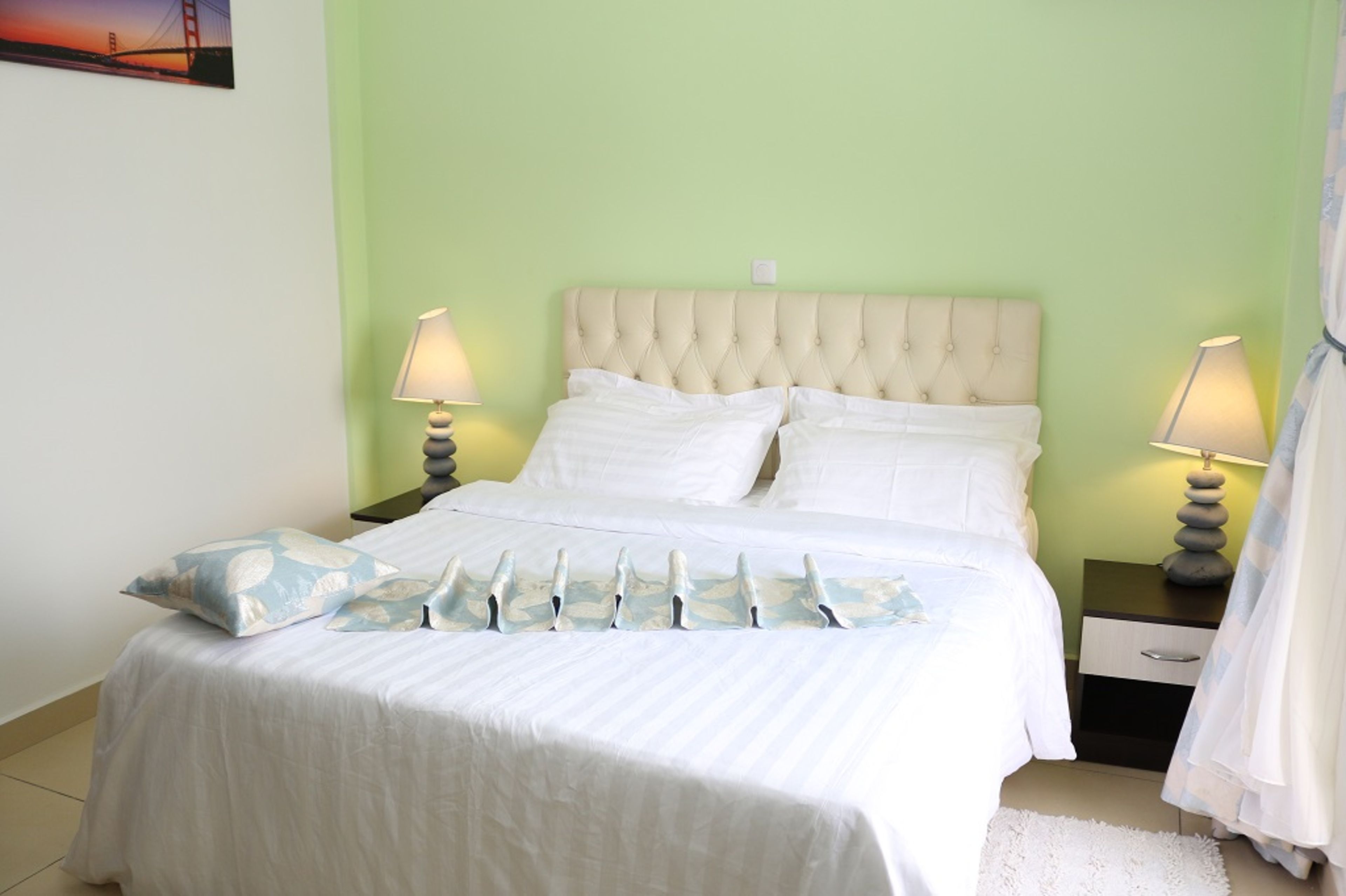 A bed with a tufted headboard, white bedding, and two bedside lamps.