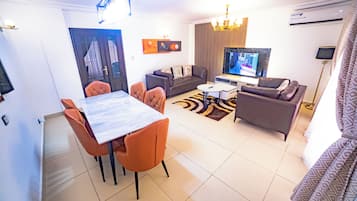 Una sala de estar moderna con comedor, un sofá, un televisor y una araña.