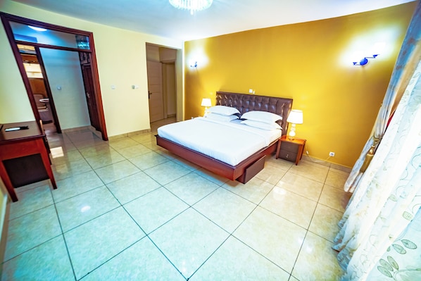 A hotel room with a bed, bedside tables, a wardrobe, and a bathroom door. - LOUMIA Residency (Douala)