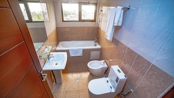 A bathroom with a bathtub, a sink, a bidet, and a toilet.