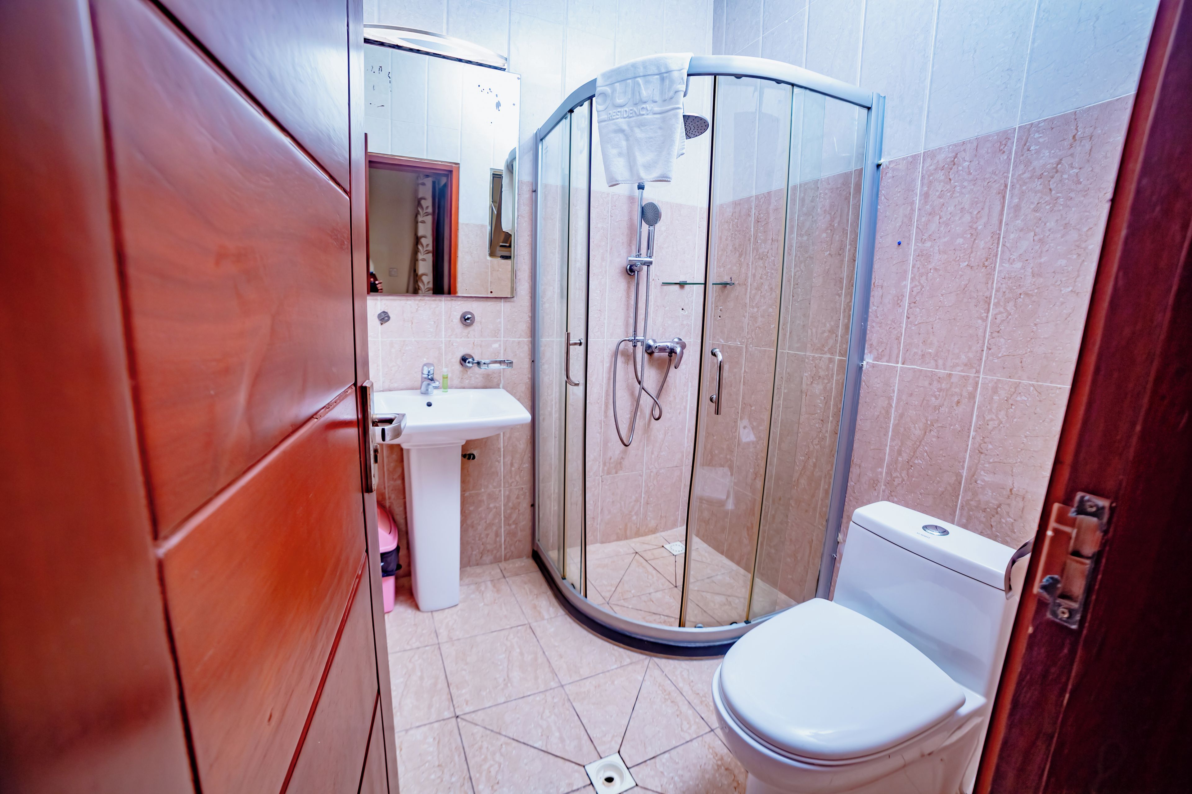 A bathroom with a glass-enclosed shower, a white sink, and a toilet.