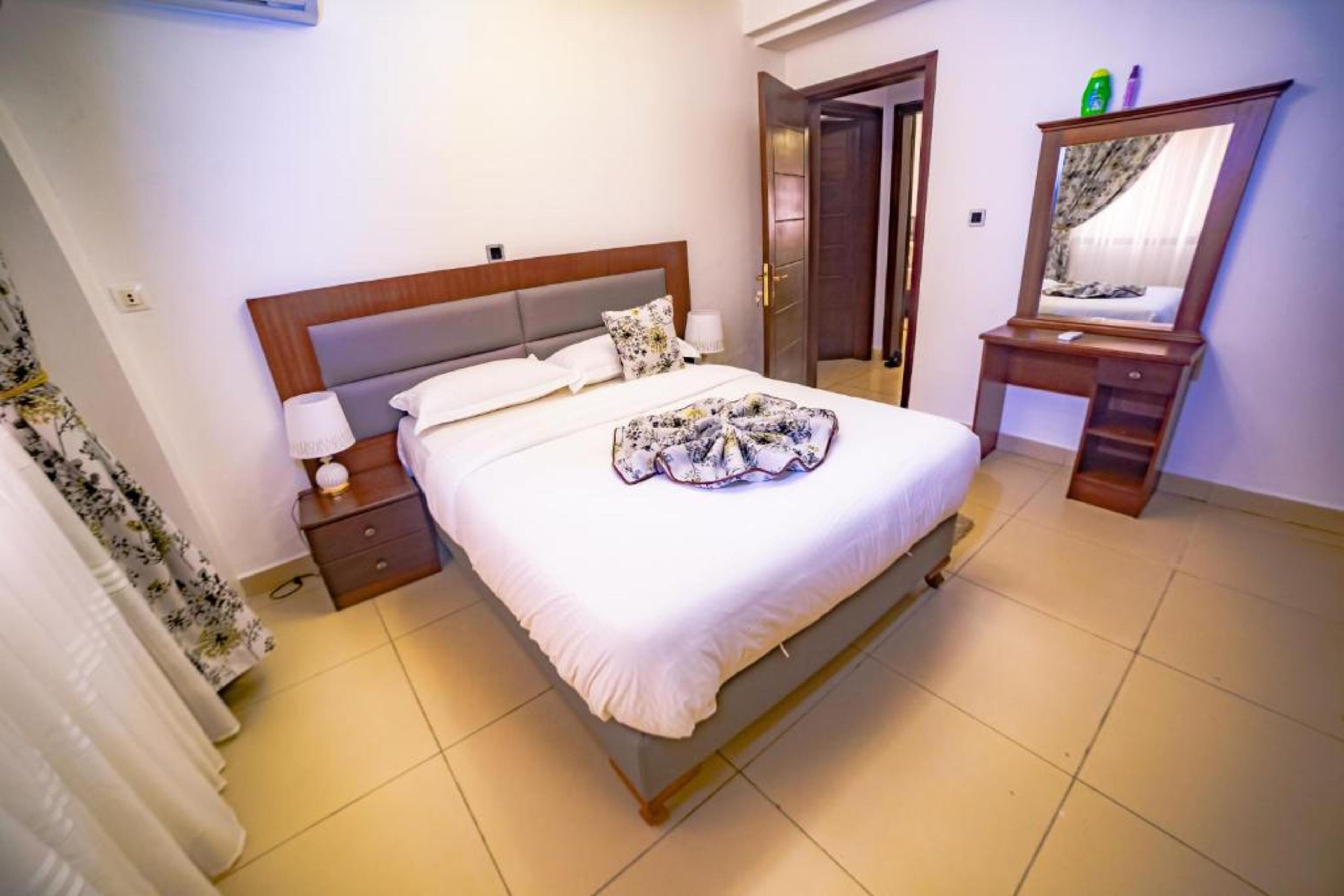 A hotel room with a bed, bedside table, lamp, and a mirror.