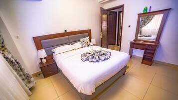 A hotel room with a bed, bedside table, lamp, and a mirror.