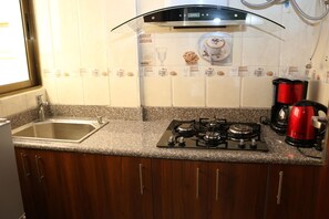 A kitchen with a granite countertop, stainless steel sink, and a gas stove.
