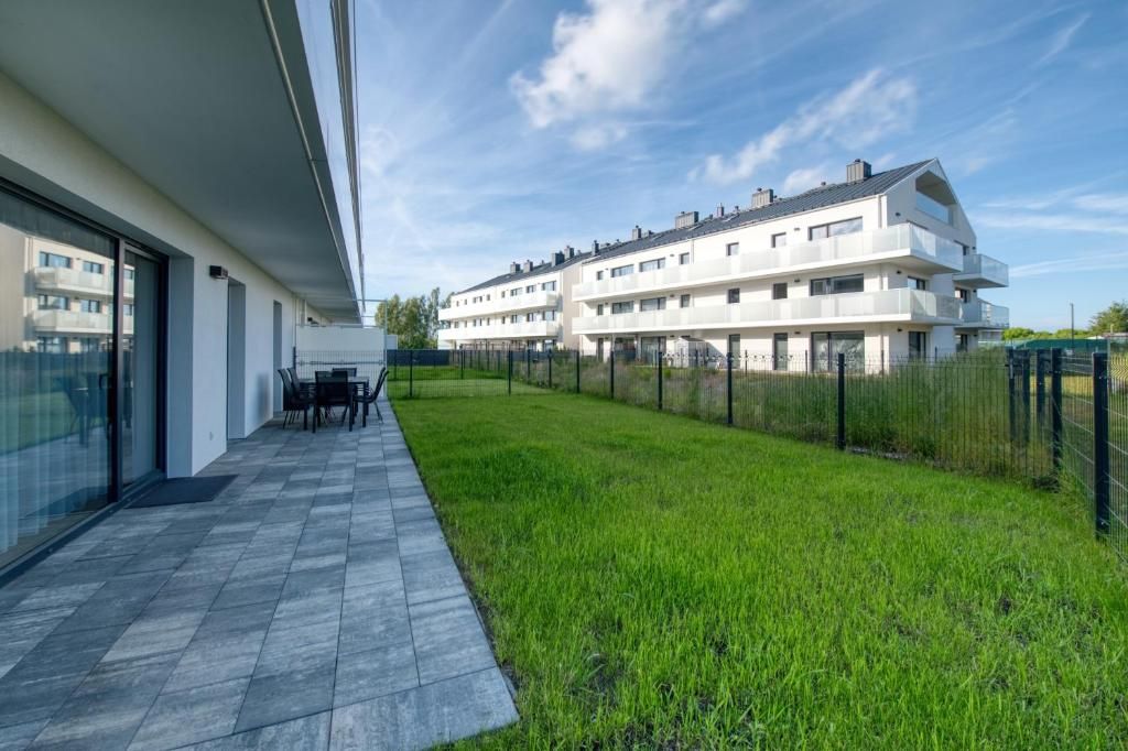 Ein moderner Wohnkomplex mit flachem Dach, großen Fenstern und einem Rasen.