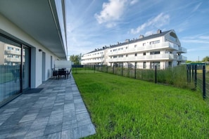 A modern apartment complex with a flat roof, large windows, and a grassy lawn. - Bałtyckie Tarasy by Q4 Apartments  (Władysławowo)