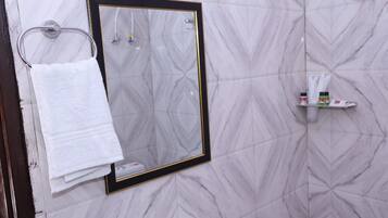 Une salle de bain avec un mur décoré d’un motif imitant le marbre, un miroir encadré, un porte-serviettes avec une serviette pliée et une étagère contenant des articles de toilette.
