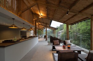 Una cocina amplia con vigas de madera, luces colgantes y vistas al bosque a través de grandes ventanales.