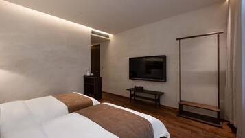 A modern hotel room with two beds, a flat-screen TV, a wooden bench, and a wardrobe.
