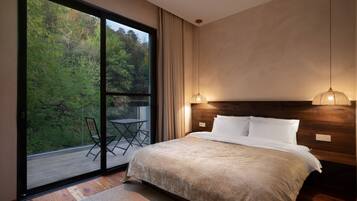 A bedroom with a large sliding glass door, a bed with white linens, a wooden headboard, and a hanging light fixture.