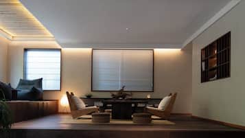 Una sala de estar moderna con un sofá, dos sillones, una mesa y un ventanal grande.