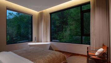 A modern bedroom with a large window, a bathtub, and a wooden floor.