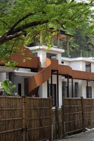 A modern building with a spiral staircase, wooden fence, and lush greenery.