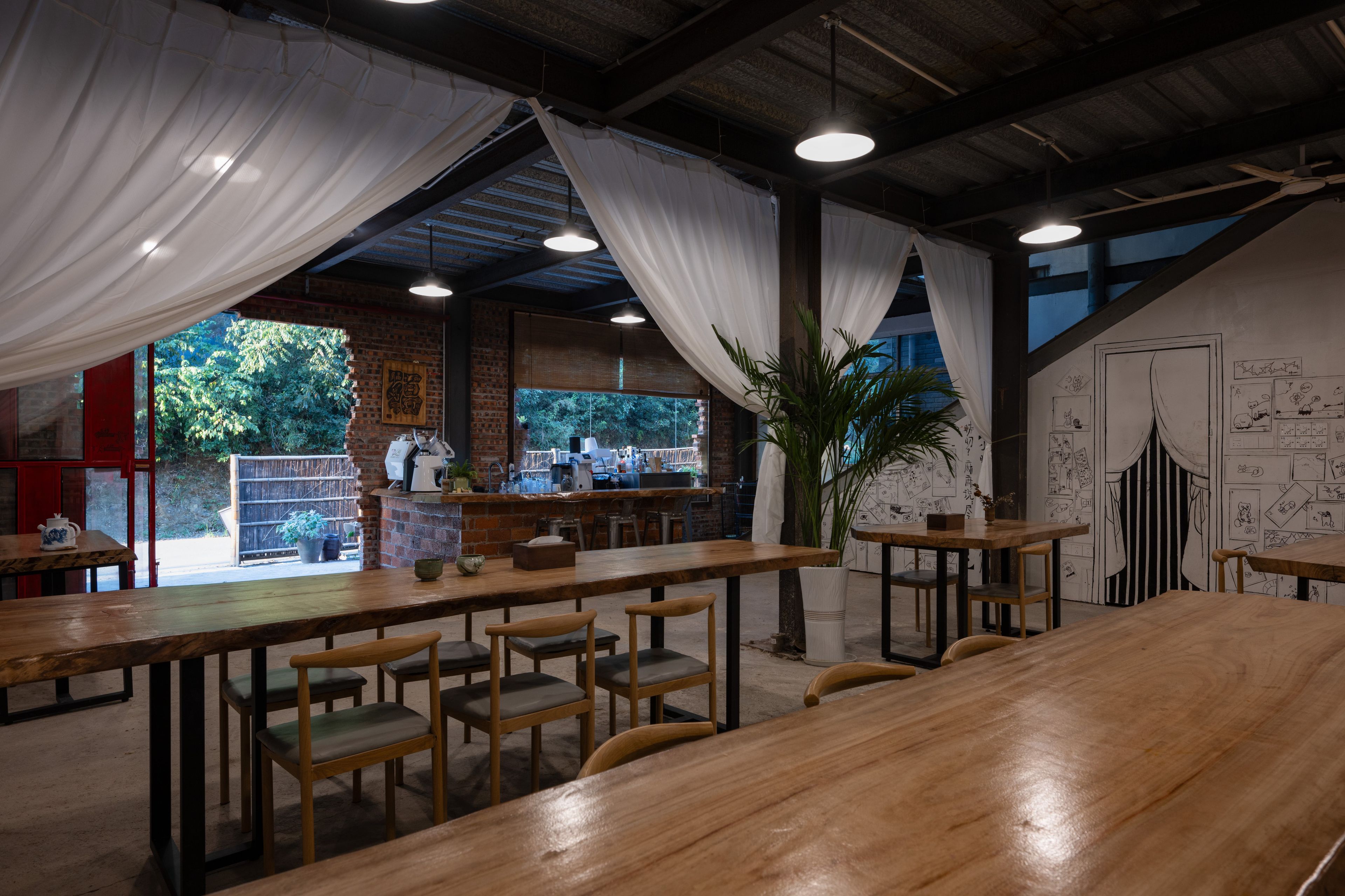 A restaurant interior with wooden tables and chairs, a bar area, and large windows overlooking a garden.