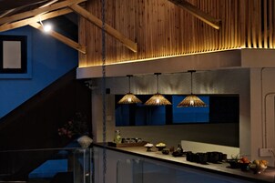 Una cocina con vigas de madera, paredes azules y tres lámparas colgantes.