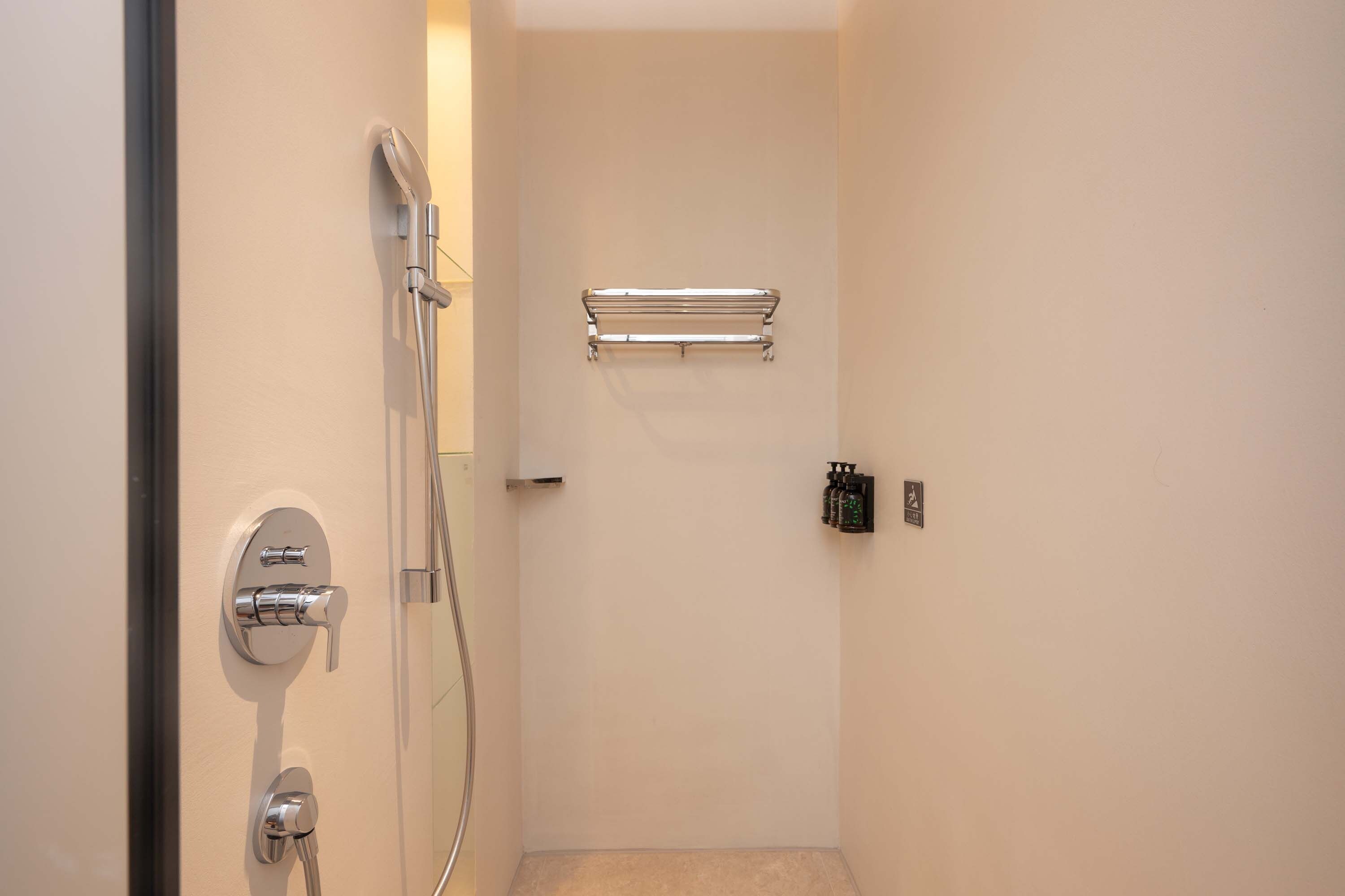 A small, enclosed shower area with a glass door, a towel rack, and a soap dispenser.