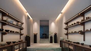 A hallway with shelves on either side displaying various pottery and bowls.