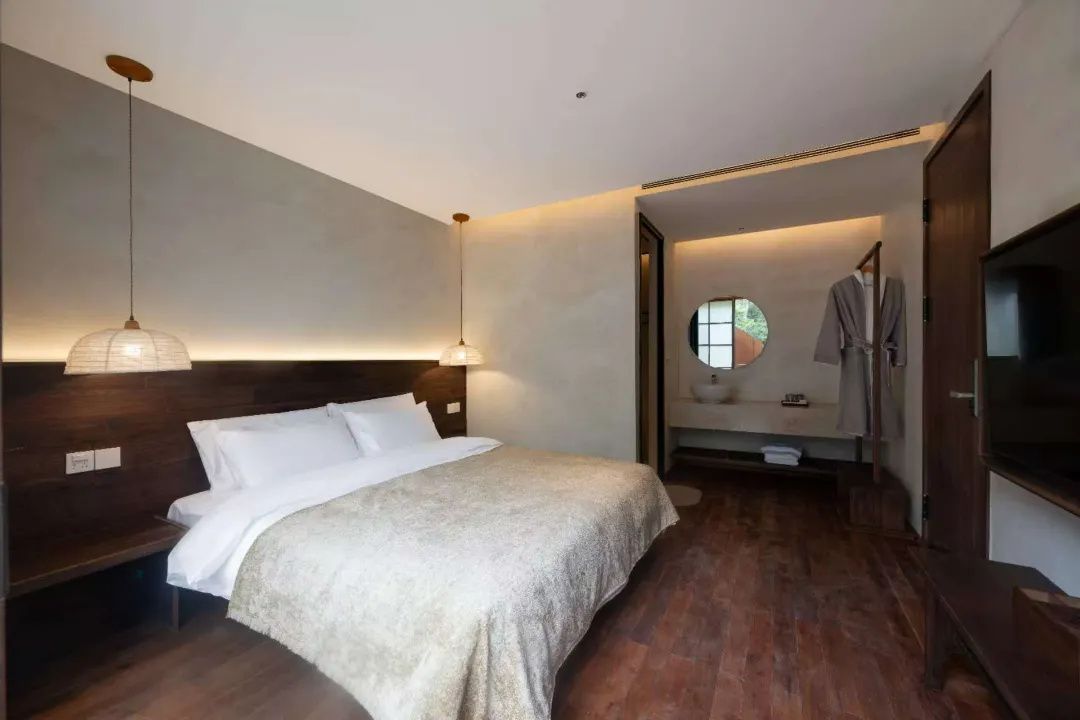 A hotel room with a large bed, a television, and a view of the outdoors through a window.