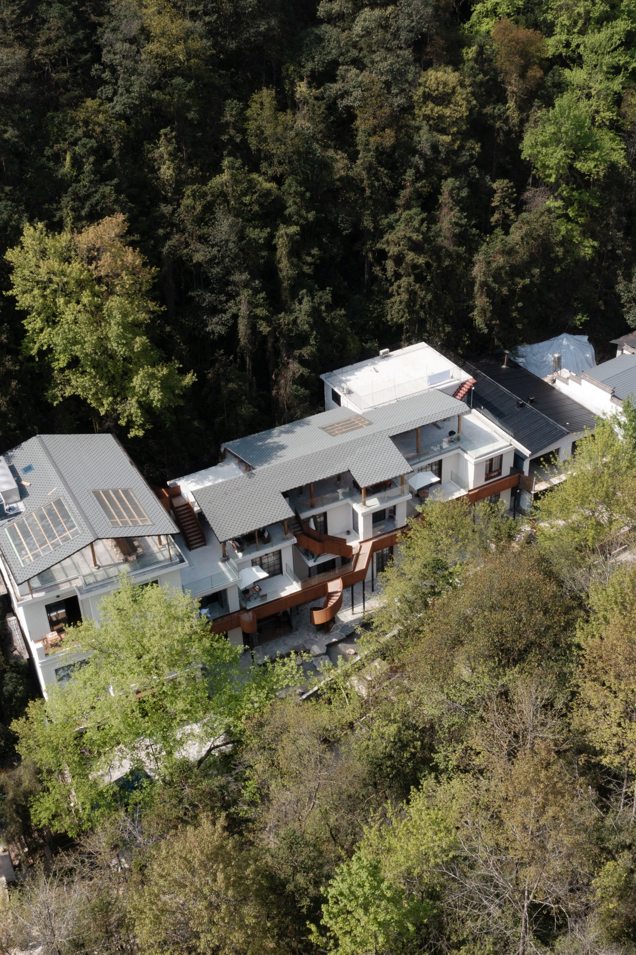 A modern multi-story building with a flat roof, surrounded by dense forest.