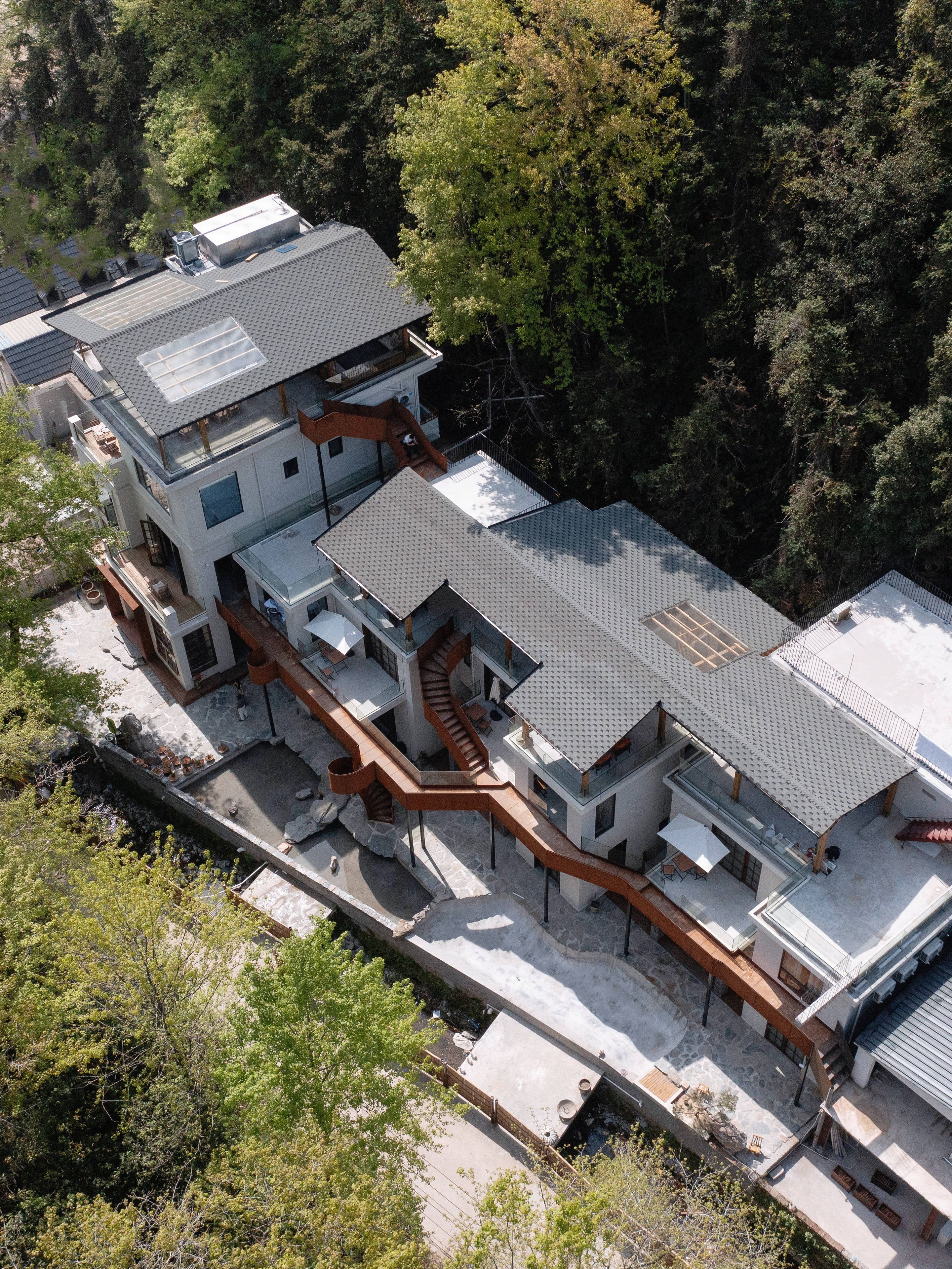 A modern multi-story building with a flat roof, surrounded by dense forest.