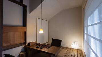A room with a wooden table, a hanging light fixture, and a large window.