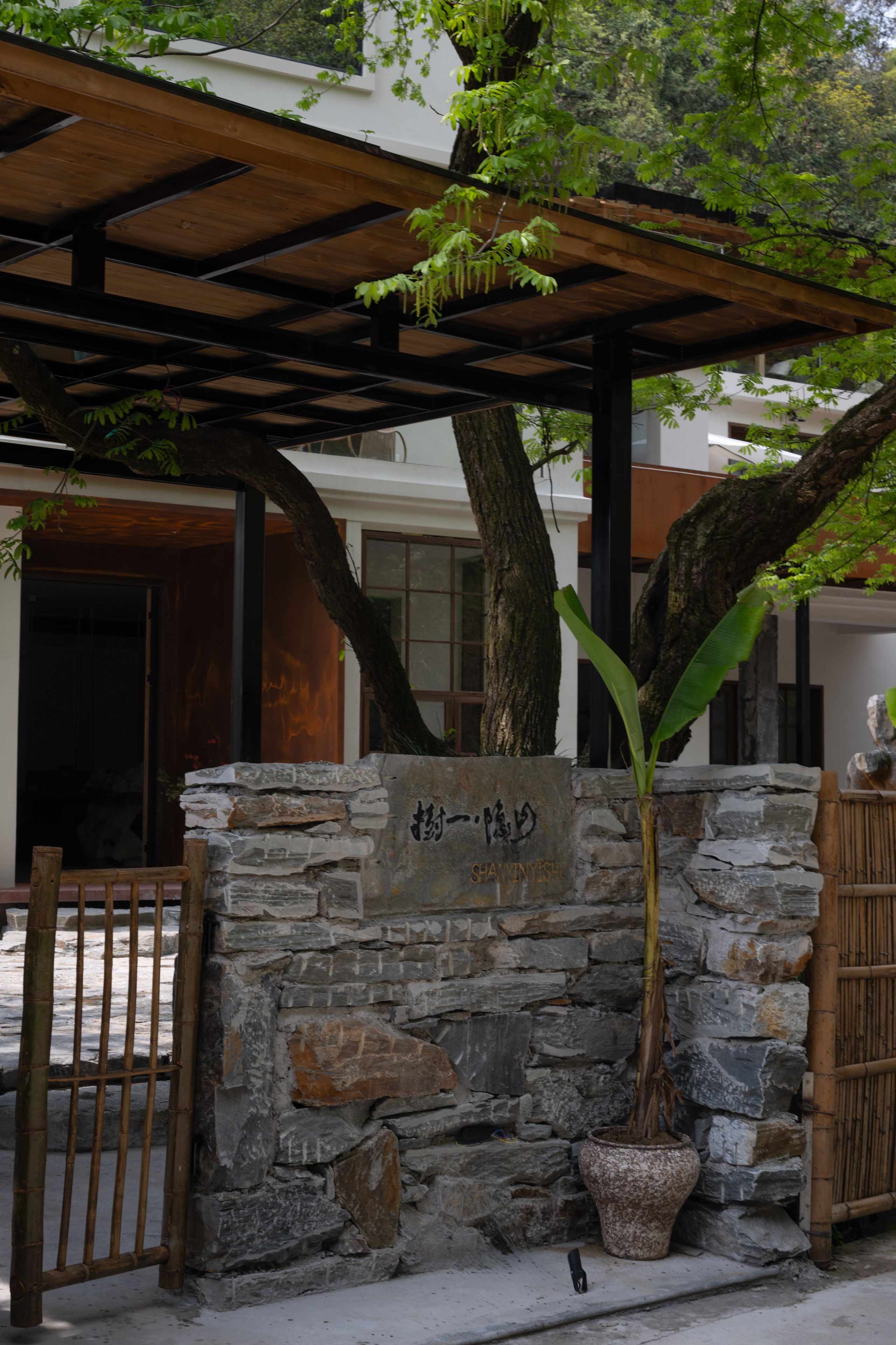 A stone wall with a potted plant and a wooden gate.