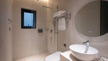Un baño moderno con un espejo grande, un lavamanos redondo y una ducha.