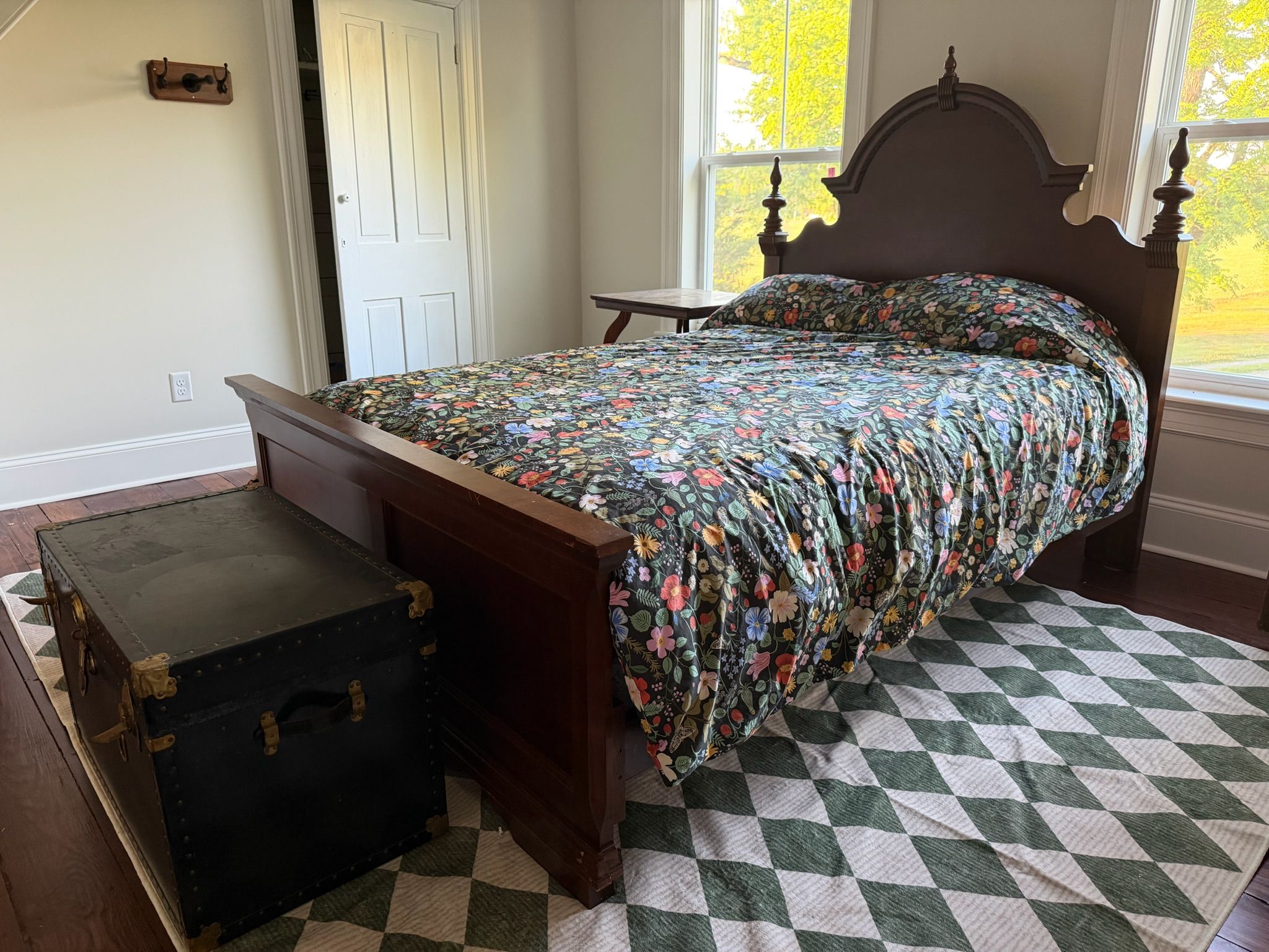 A bedroom with a bed, a chest of drawers, a window, and a door.