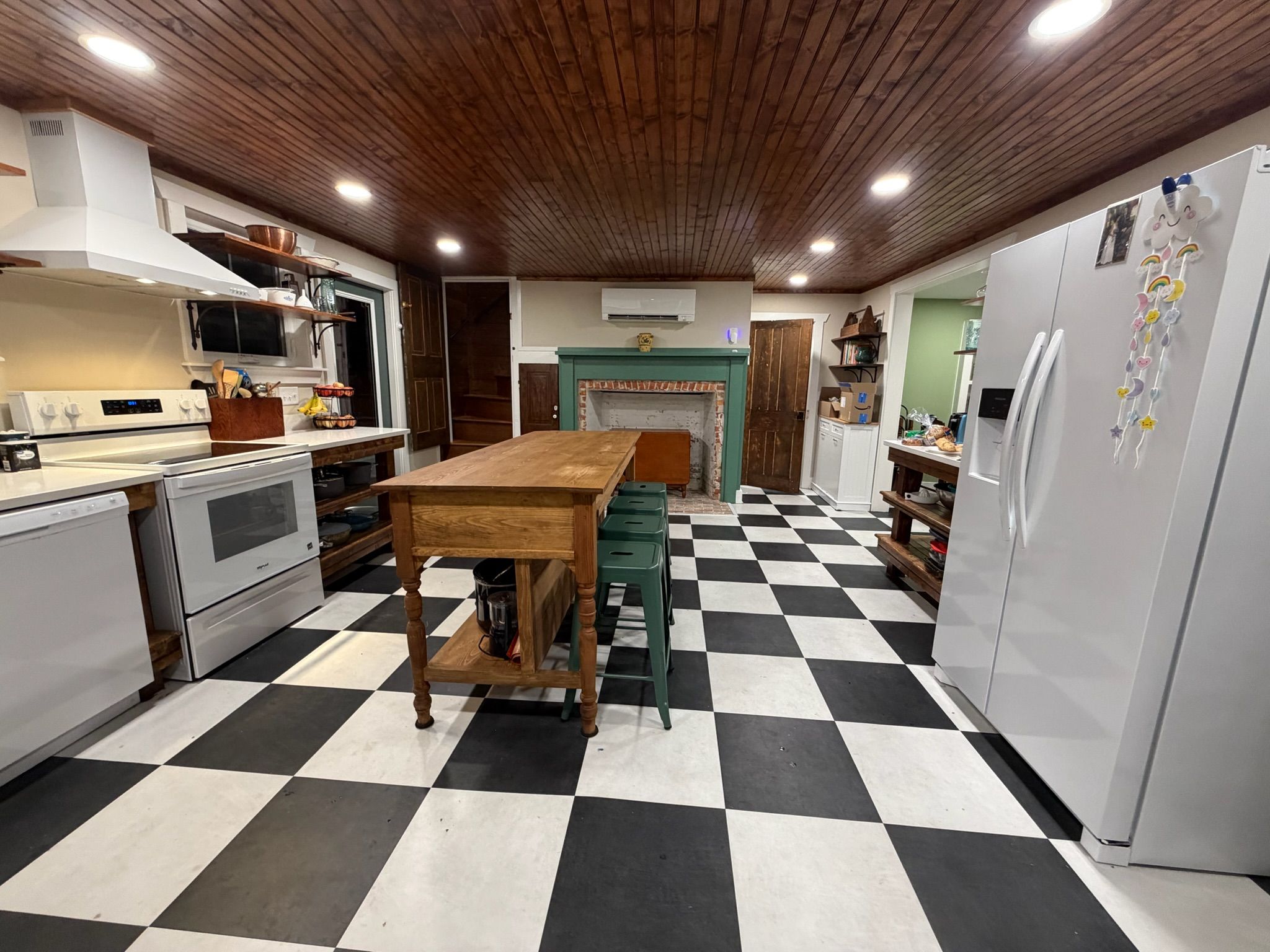 A kitchen with a checkered floor, wooden ceiling, and white appliances.