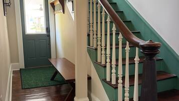 A staircase with a wooden handrail and white balusters, leading to a landing with a bench and a door.