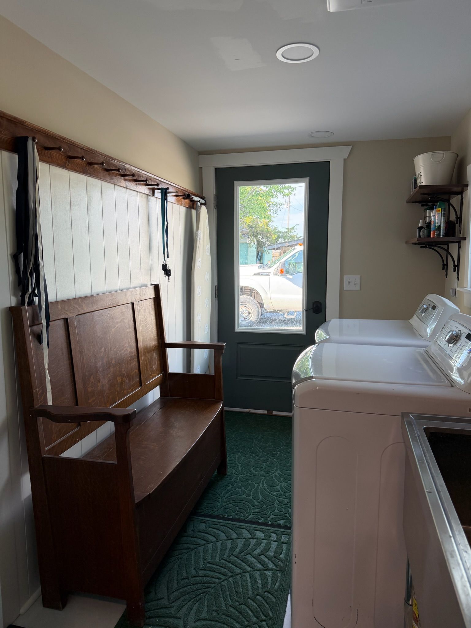 A laundry room with a bench, a washing machine, and a dryer.
