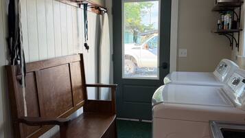 A laundry room with a bench, a washing machine, and a dryer.