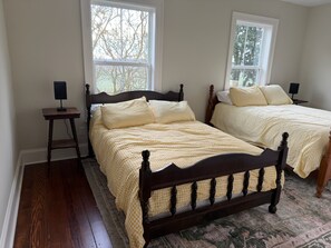 Un dormitorio con dos camas, piso de madera y alfombra estampada.