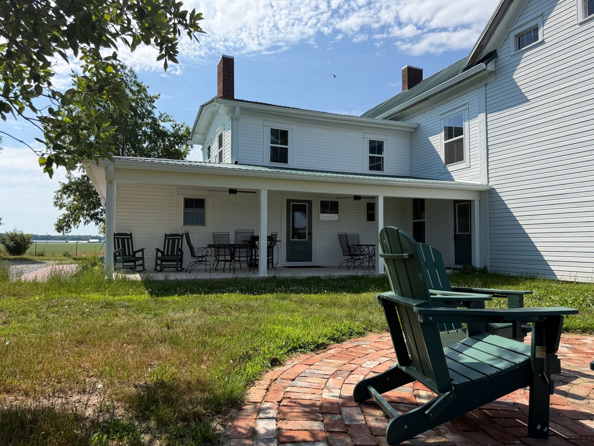 A two-story house with a covered porch and outdoor seating.