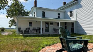 A two-story house with a covered porch and outdoor seating.