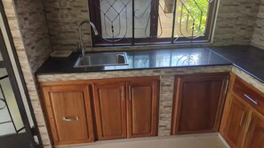 Una cocina con encimera negra, pileta de acero inoxidable y armarios de madera.