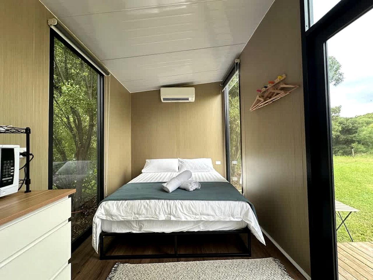 A bedroom with a bed, a microwave, and a window.