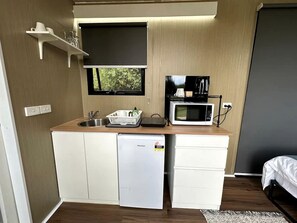 Eine kleine Küchenzeile mit Kühlschrank, Mikrowelle und Spüle.