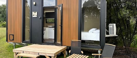 A modern, compact mobile home with a dining area, a bed, and a small kitchenette.