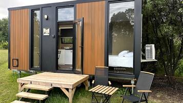 A modern, compact mobile home with a dining area, a bed, and a small kitchenette.