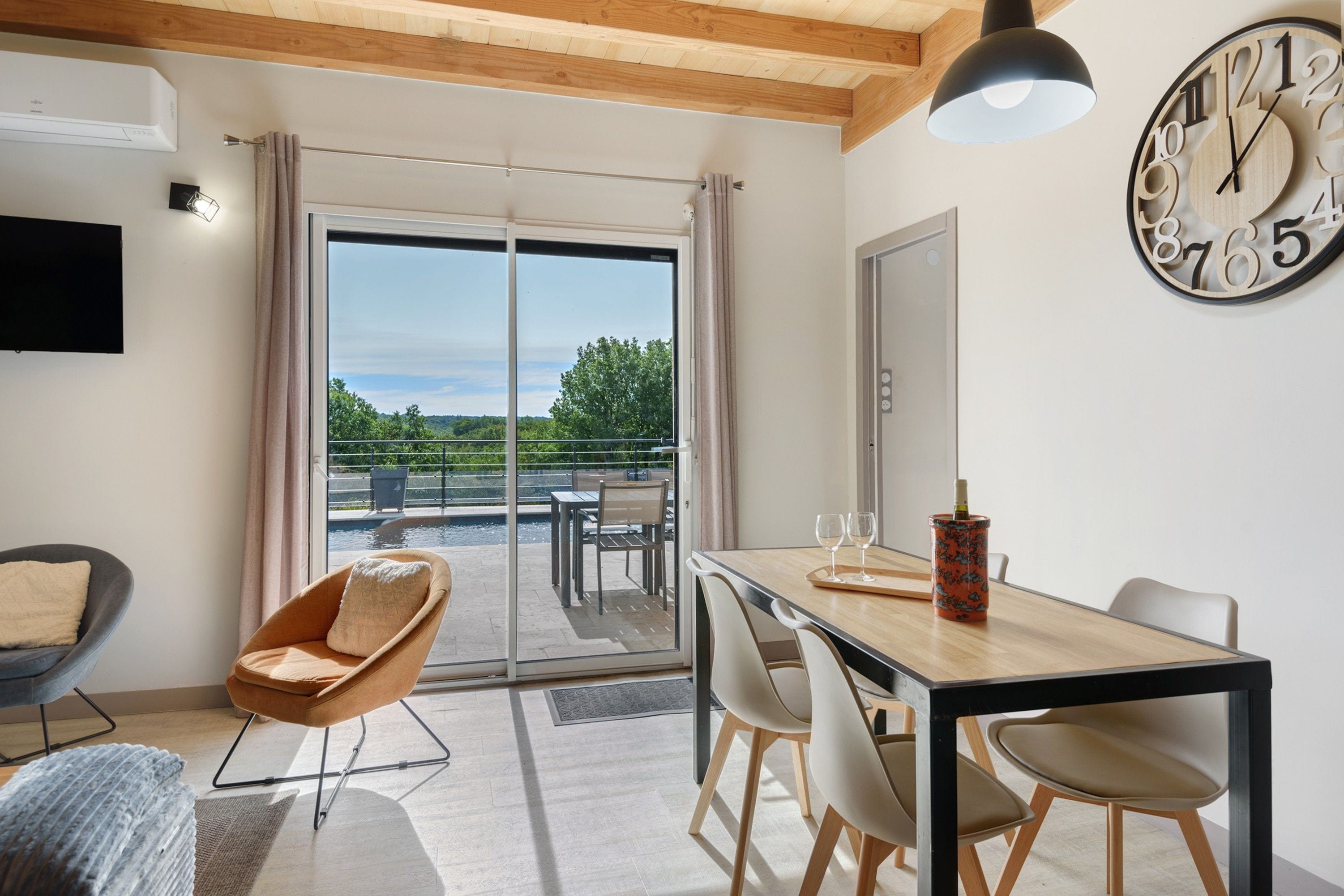 Une pièce moderne comprenant une table à manger, des chaises, un canapé, un téléviseur et une grande horloge murale.