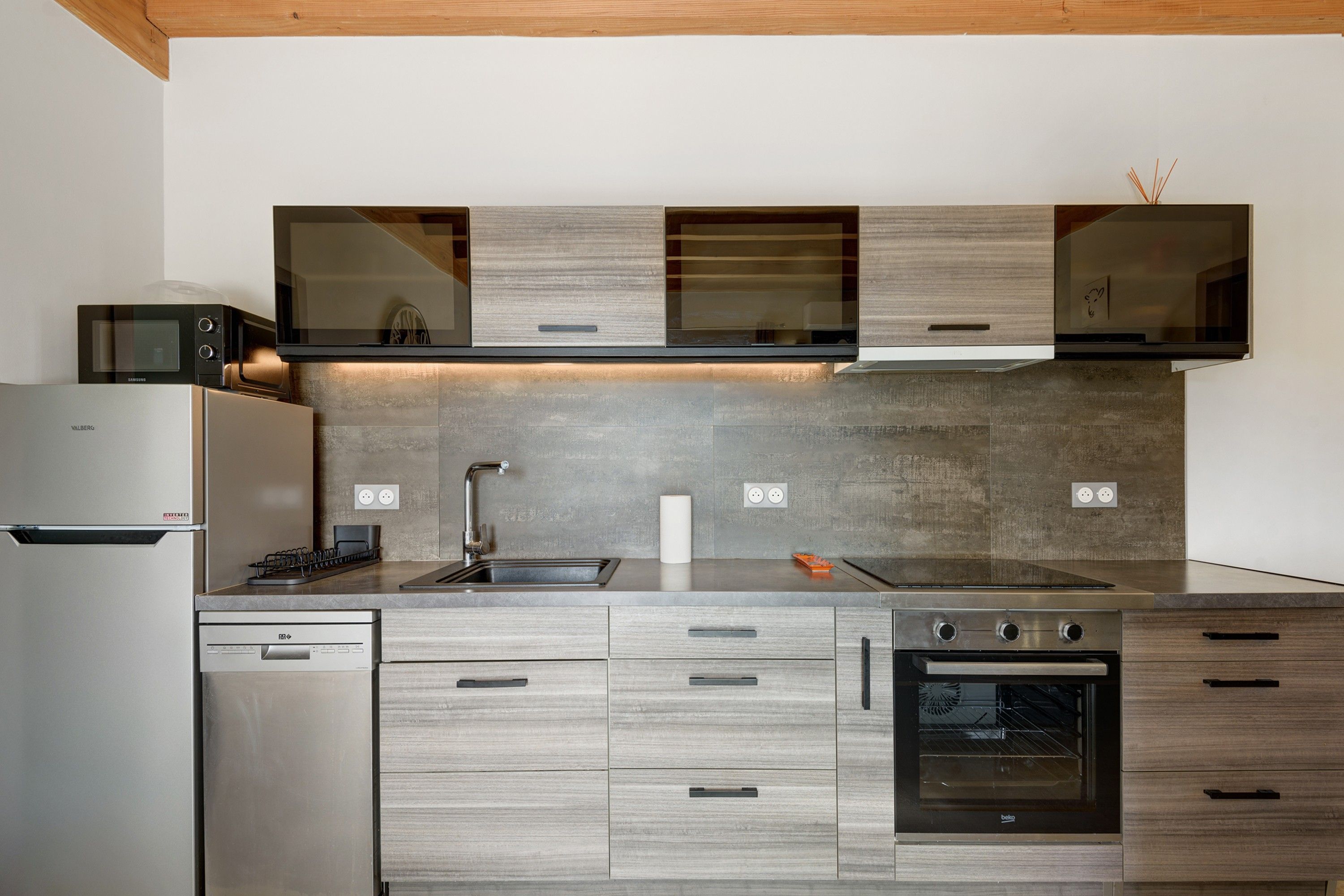 A modern kitchen with a stainless steel refrigerator, a built-in microwave, a gas stove, and a built-in oven.